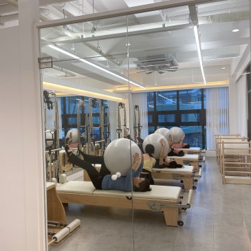 리포머에 누워 짐볼을 안고 상체를 든 그룹 수업.