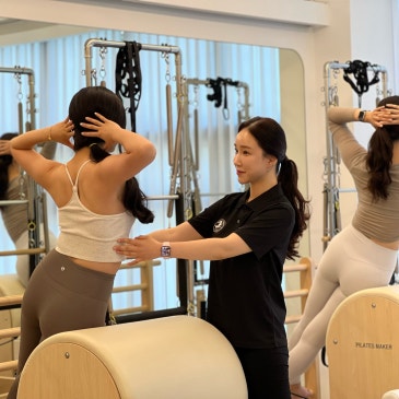 바렐 앞에서 두 손을 머리 뒤에 대고 선 회원의 등을 잡아 주는 강사.
