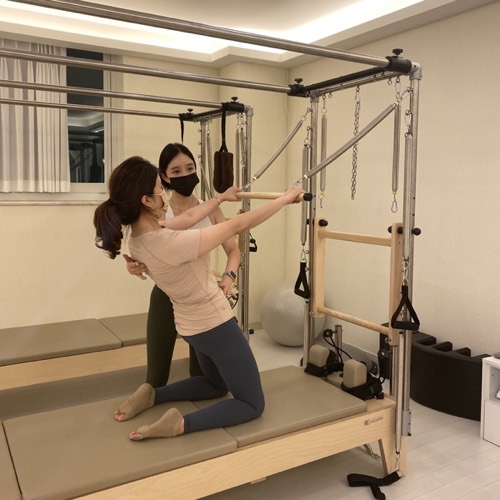 강사가 회원의 캐딜락 동작을 옆에서 잡아 주는 모습.